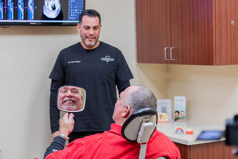 john walker,dds showing patient their smile after dental implant procedure