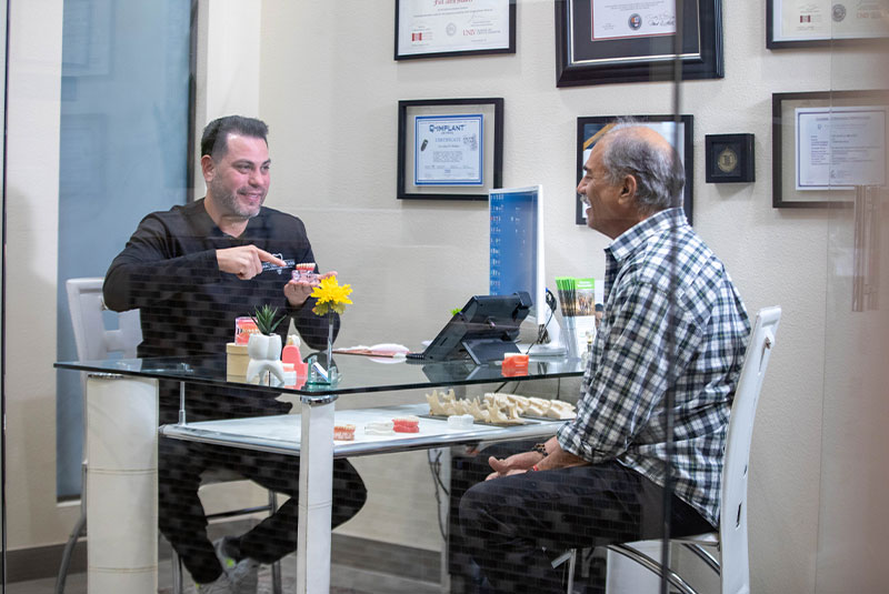john walker,dds showing patient a model of dental implants