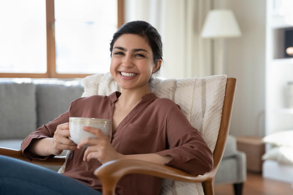 Portrait of smiling beautiful indian ethnicity woman resting in cozy armchair
